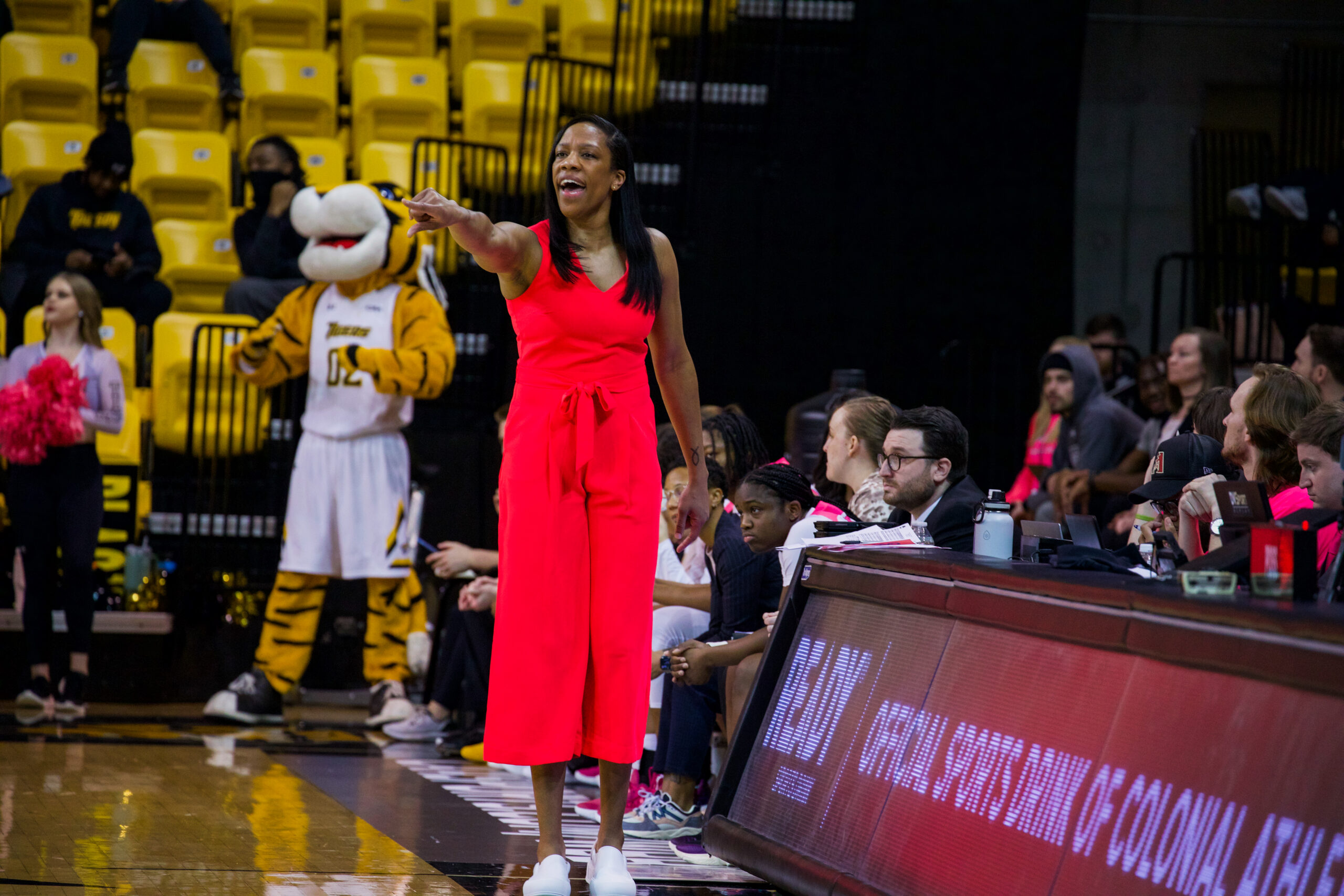 A picture of Towson Women's Basketball Head Coach Laura Harper as she stands in the bench area during a game on March 10.